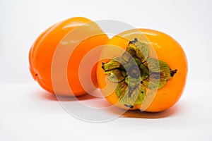 Poltava, Ukraine - 1 May, 2021: Two ripe orange persimmons Diospyros kaki on a white background photo