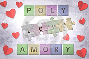 Polyamory word made with wooden colored puzzle pieces and red paper hearts on a table photo