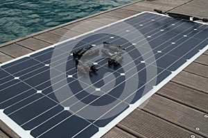 Polycrystalline flexible solar panel and mc 4 connectors on the background on the teak deck of the bert