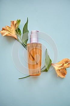 Polyglutamic Acid and multiuse care products on blue background with alstroemeria flowers decorations photo
