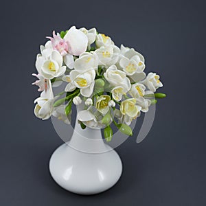 Polymer clay flower bouquet in a white vase on a gray background photo