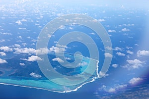 Polynesia. The atoll in ocean through clouds. Aerial view.