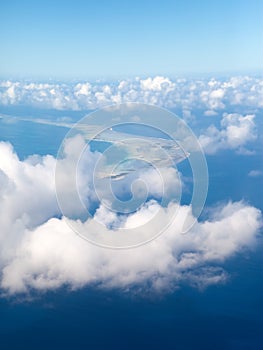 Polynesia. The atoll ring in ocean is visible through clouds. Aerial view.