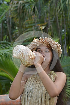 Polynesian Cook Islander woman blowing conch shell in Rarotonga