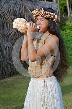 Polynesian Cook Islander woman blowing conch shell in Rarotonga photo