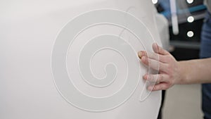 Polyurethane vinyl film pasted on a car body close-up. Retrofitting the car with a solid white protective film, the