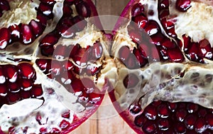 Pomegranate divided in two half on a wooden background viewed from above. Concept of winter and autumn months like october,