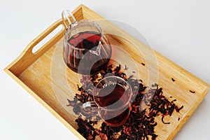 Pomegranate flowers tea is brewed in glass teapot and poured into a cup. Bamboo tray. Beautiful ruby infusion