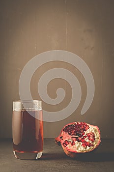 Pomegranate fruit and juice in glass/Pomegranate fruit and juice in glass on dark background with copy space