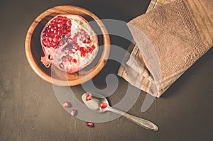 pomegranate fruit in a wooden bowl/pomegranate fruit in a wooden bowl and seeds on the table and in a spoon, top view