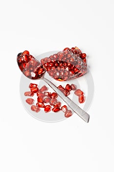 Pomegranate fruits and pomegranate seeds in spoon on white background.
