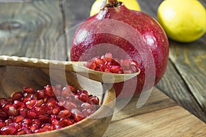 Pomegranate grains in a wooden bowl closeup