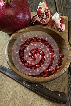 Pomegranate grains in a wooden bowl closeup