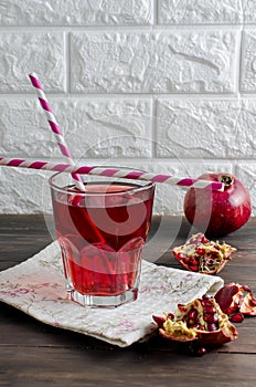 Pomegranate juice in glass and pomegranates on dark old wooden