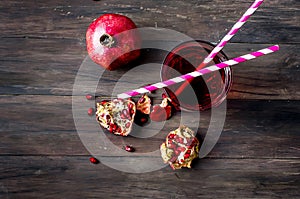 Pomegranate juice in glass and pomegranates on dark old wooden