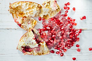 Pomegranate peel and seeds over white wooden background.