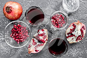 Pomegranate seeds, sliced fruit and juice in glass on stone background top view