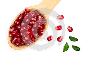 Pomegranate seeds in wooden spoon with leaves isolated on white background. Top view. Flat lay pattern