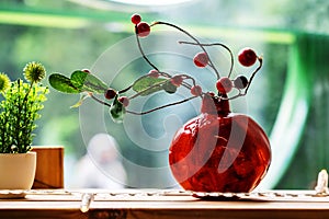Pomegranate-shaped vase with dry branches and red berries. Decorating the room with decorative fruits and plants. Close-up. photo