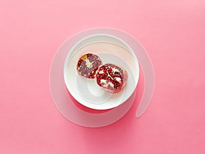 Pomegranate sliced in white bowl viewed from above over a pink or fuschia background