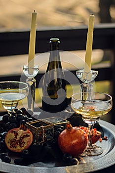 pomegranate, wine and candles on a tray with jewelry and caskets. Gothic still life on the street. Sliced pomegranate on a silver