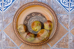 Pomegranates on pattered wooden plate. Tiles