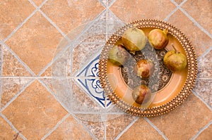 Pomegranates on pattered wooden plate. Tiles