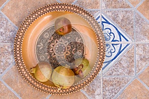 Pomegranates on pattered wooden plate. Tiles