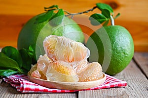Pomelo fruit on wooden background, fresh green pomelo peeled on plate and green leaf frome pomelo tree , pummelo , grapefruit in
