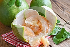 Pomelo fruit on wooden background, fresh green pomelo peeled on pomelo skin and leaf frome pomelo tree , pummelo , grapefruit in