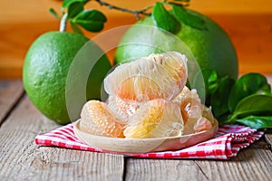 Pomelo fruit on wooden plate  background, fresh green pomelo peeled and leaf frome pomelo tree , pummelo , grapefruit in summer