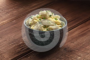 Pomme puree, a photo of a bowl of mashed potatoes with herbs on a dark rustic background photo