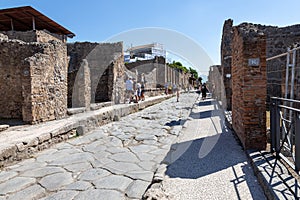 Pompeii, Company, Italy - June 25, 2019: typical street of ancient Pompeii. Tourists visit the ruins of the ancient Roman city of