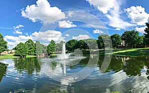 Pond with cloud reflection and water fountain in small American neighborhood