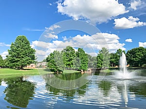 Pond with cloud reflection and water fountain in small American neighborhood