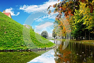 Pond with a forest and hill with castle buildings against sky wi