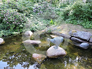 Pond with reflection. statue, blooming bushes in the park, in Kotka, Finland