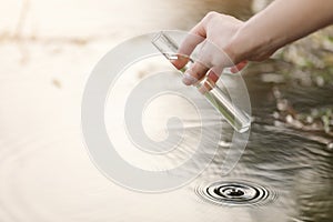 Pond water pollution concept. Scientist biologist and researcher takes samples of dirty water from a pond into a test