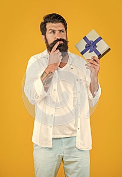 pondering man with gift box in studio. man with gift box on background.