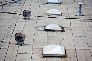 Ponding water pooling on the settled flat roof Turbine vents and skylight roof windows on the rooftop of an industrial building