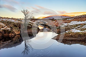 Pont Ar Elan, Elan Valey, wales snowy scene of Afon Elan flowing through a bridge in winter with lone tree reflected in water and