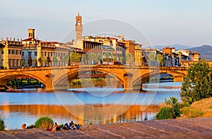 The Ponte Santa Trinita over Arno river at sunset, seen from the attractive promenade Lungarno Guicciardini in Florence. .