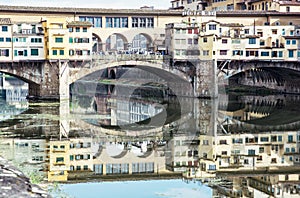 Ponte Vecchio is mirrored in the river Arno, Florence, Italy, cu