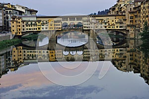 The Ponte Vecchio reflects onto the Arno river in Florence , Italy