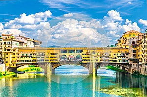 Ponte Vecchio stone bridge with colourful buildings houses over Arno River blue turquoise water in Florence, Italy