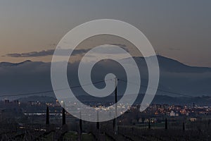 Pontedera and Monte Serra partially shrouded in fog at sunset, Tuscany, Italy