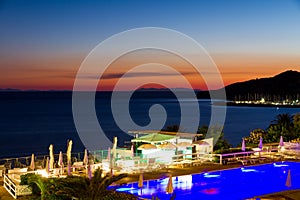 Pool and bar by the sea at sunset in summer in Italy