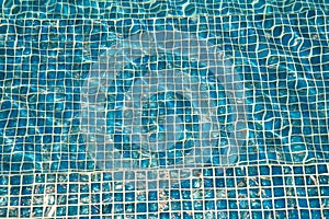 A pool with blue ceramic tiles and water ripple effect. Refection of Blue water in Swimming pool with Ripple. close-up