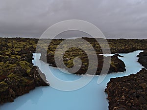 Pool with blue colored thermal water in a moss covered lava field near spa resort Blue Lagoon in Grindavik, Reyjanes, Iceland.