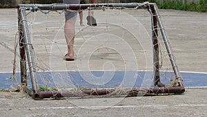 Pool boy kicking old football have laceration and net laceration small goal.